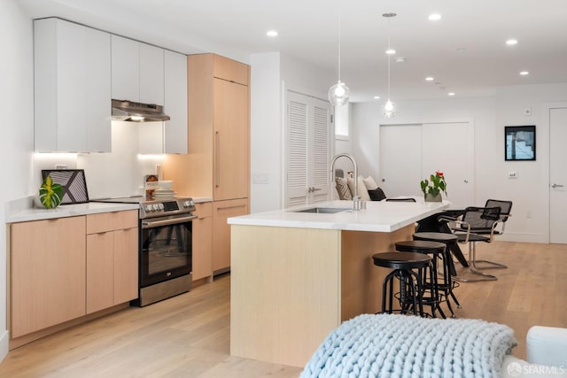 kitchen with pendant lighting, light brown cabinetry, sink, a kitchen island with sink, and stainless steel electric range