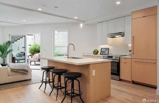 kitchen with sink, a kitchen island with sink, hanging light fixtures, white cabinets, and stainless steel range with electric cooktop