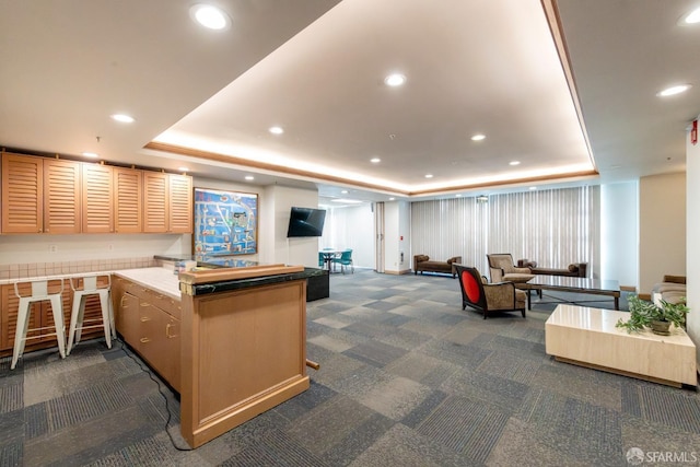 interior space featuring recessed lighting, a peninsula, open floor plan, dark carpet, and a raised ceiling