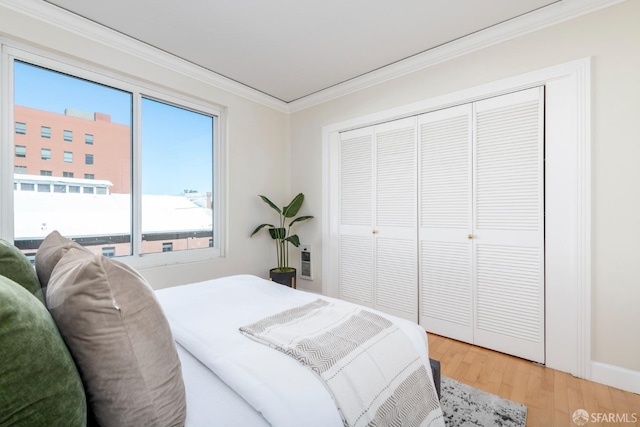 bedroom with a closet, wood finished floors, and crown molding