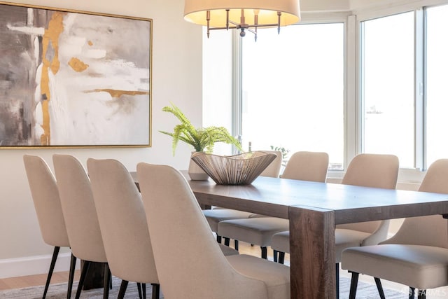 dining space with an inviting chandelier, a healthy amount of sunlight, baseboards, and wood finished floors