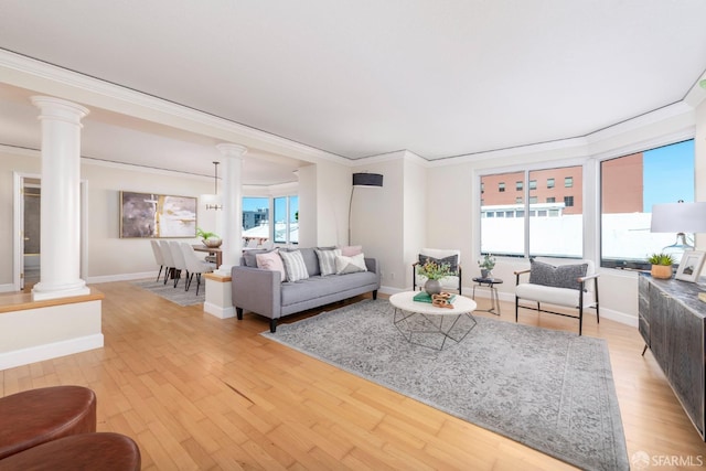 living room with ornamental molding, light wood-type flooring, decorative columns, and baseboards