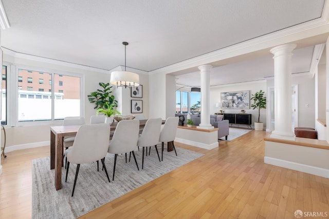 dining room featuring light wood-type flooring, plenty of natural light, and decorative columns