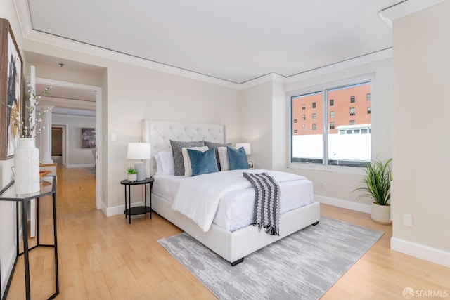 bedroom featuring light wood finished floors, baseboards, and crown molding