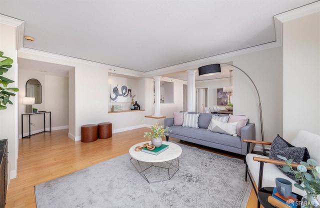 living area featuring ornate columns, crown molding, baseboards, and wood finished floors