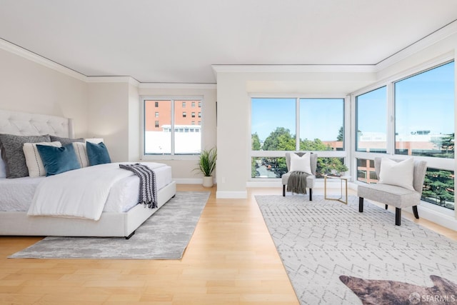 bedroom featuring baseboards, ornamental molding, and light wood-style floors