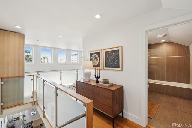 hall featuring light wood finished floors, recessed lighting, and vaulted ceiling