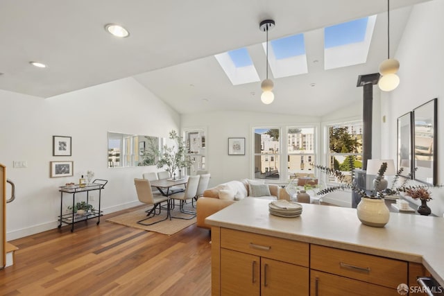 kitchen with light countertops, a skylight, light wood-style floors, brown cabinets, and pendant lighting