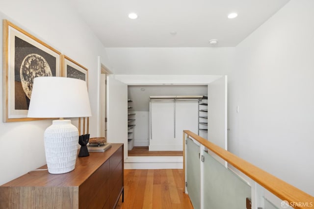 corridor featuring light wood-type flooring, recessed lighting, and an upstairs landing