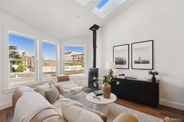 living area with a skylight, lofted ceiling, baseboards, a wood stove, and wood finished floors