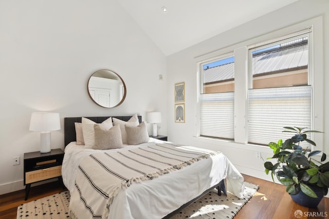 bedroom featuring wood finished floors, high vaulted ceiling, and baseboards
