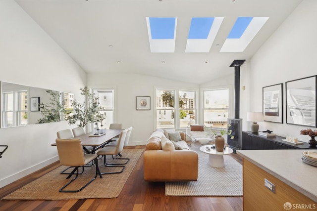living room featuring a wood stove, a skylight, wood finished floors, lofted ceiling, and baseboards