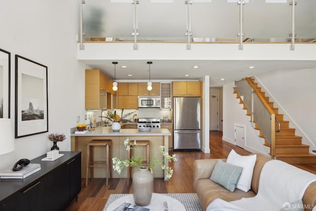 living area with dark wood-type flooring, stairs, a towering ceiling, and recessed lighting