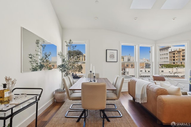 dining room featuring wood finished floors, lofted ceiling, baseboards, and a skylight