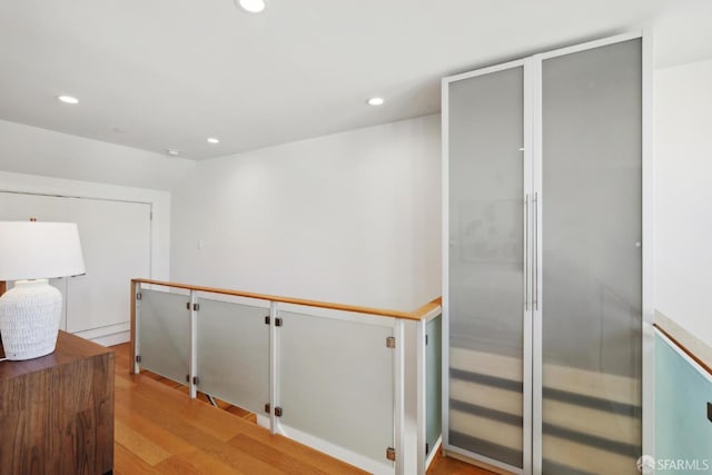 corridor featuring recessed lighting, light wood-style floors, and an upstairs landing