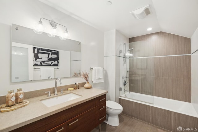 bathroom featuring toilet, tiled shower / bath, vanity, and vaulted ceiling