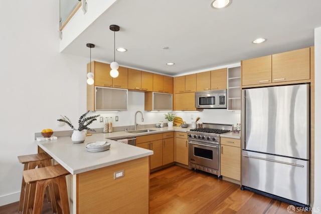 kitchen with appliances with stainless steel finishes, a sink, a peninsula, light countertops, and recessed lighting