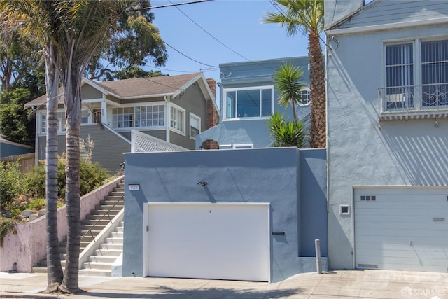 939 Innes Ave, San Francisco, CA 94124 - view of front facade with stucco siding, concrete driveway, stairway, and an attached garage