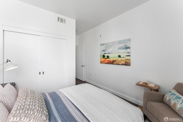 bedroom with visible vents, baseboards, a closet, and wood finished floors