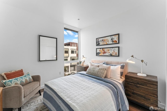 bedroom featuring floor to ceiling windows, baseboards, and wood finished floors