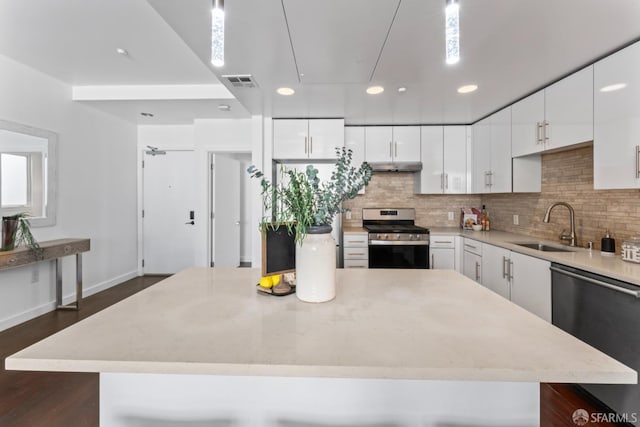 kitchen with visible vents, a kitchen island, under cabinet range hood, appliances with stainless steel finishes, and a sink