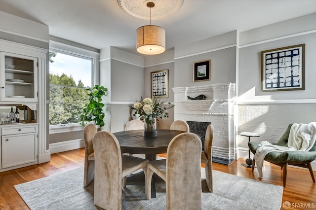 dining area featuring plenty of natural light, light hardwood / wood-style floors, and a brick fireplace