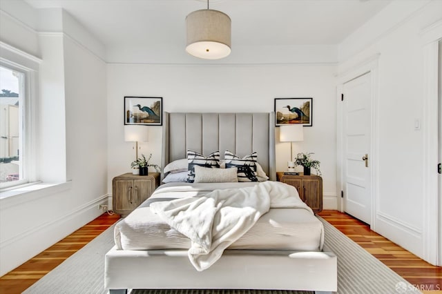 bedroom featuring multiple windows and light hardwood / wood-style flooring