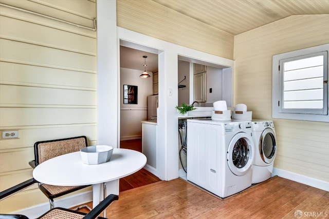 laundry room with separate washer and dryer, hardwood / wood-style floors, and wooden walls