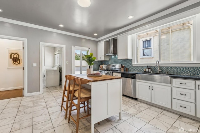 882 56th St, Oakland, CA 94608 - kitchen featuring appliances with stainless steel finishes, wall chimney exhaust hood, butcher block countertops, light marble finish floors, and ornamental molding