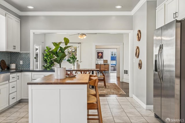882 56th St, Oakland, CA 94608 - kitchen with stainless steel fridge with ice dispenser, light marble finish floors, crown molding, butcher block countertops, and decorative backsplash