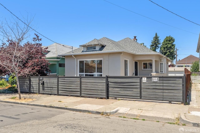 882 56th St, Oakland, CA 94608 - bungalow featuring stucco siding, a fenced front yard, a shingled roof, and a gate