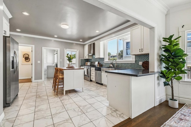 882 56th St, Oakland, CA 94608 - kitchen featuring appliances with stainless steel finishes, crown molding, a breakfast bar area, a peninsula, and backsplash