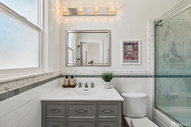 882 56th St, Oakland, CA 94608 - full bathroom with vanity, healthy amount of natural light, tile walls, bath / shower combo with glass door, and wainscoting
