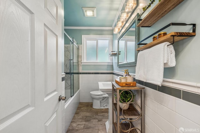 882 56th St, Oakland, CA 94608 - bathroom with tile walls, combined bath / shower with glass door, ornamental molding, wood finished floors, and wainscoting