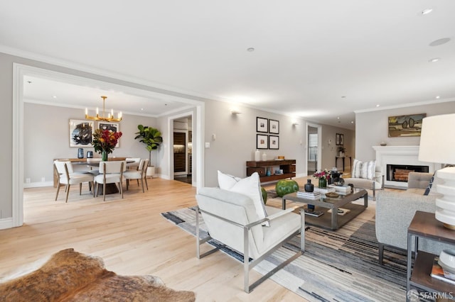 living room with crown molding, light wood-type flooring, and a notable chandelier