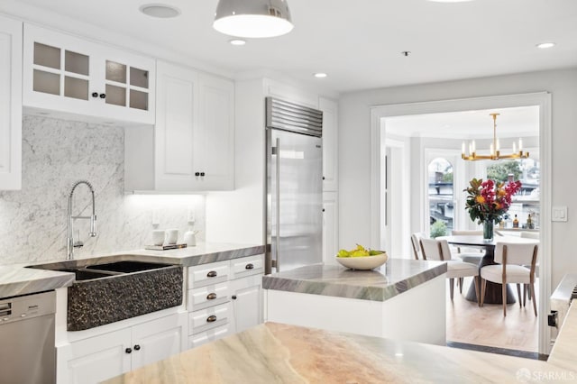 kitchen with decorative light fixtures, sink, dishwashing machine, white cabinets, and stainless steel built in fridge