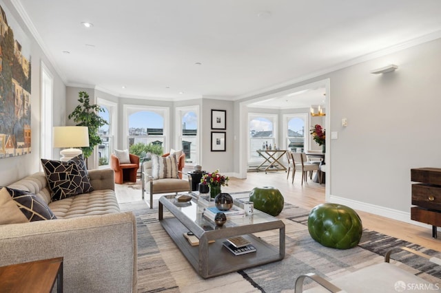 living room with ornamental molding, plenty of natural light, light hardwood / wood-style flooring, and a notable chandelier