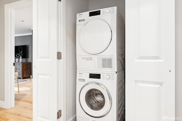 laundry room with light hardwood / wood-style floors, ornamental molding, and stacked washer and clothes dryer