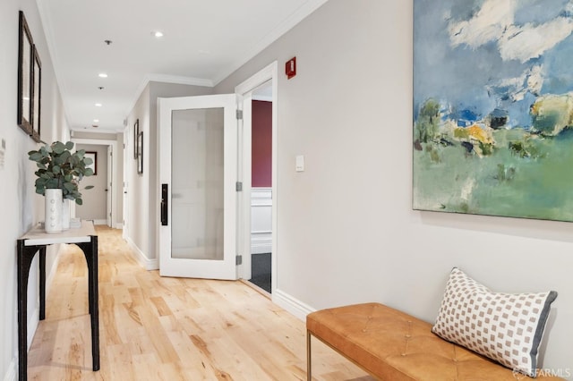 hallway with ornamental molding and light hardwood / wood-style floors