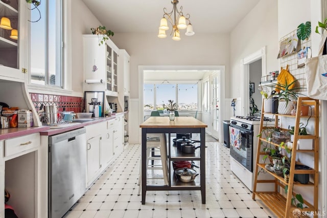 522 Liberty St, San Francisco, CA 94114 - kitchen with stainless steel dishwasher, white cabinets, white range with gas stovetop, light floors, and a notable chandelier