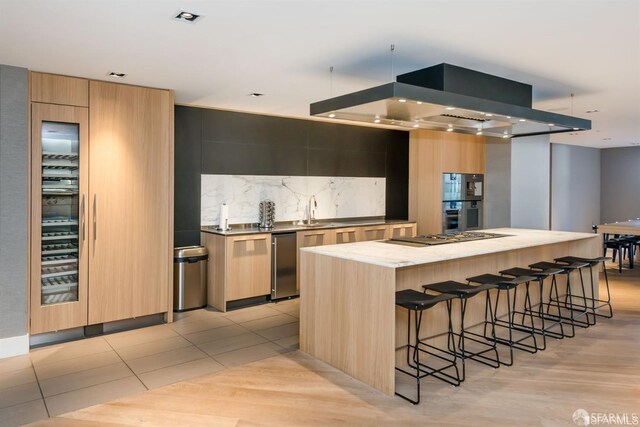 333 Beale St Unit 5I, San Francisco, CA 94105 - kitchen featuring modern cabinets, a spacious island, wall chimney range hood, a breakfast bar area, and backsplash