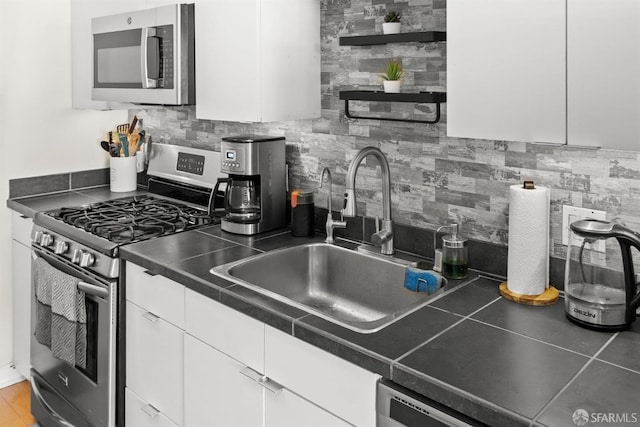 kitchen featuring decorative backsplash, sink, stainless steel appliances, and white cabinets