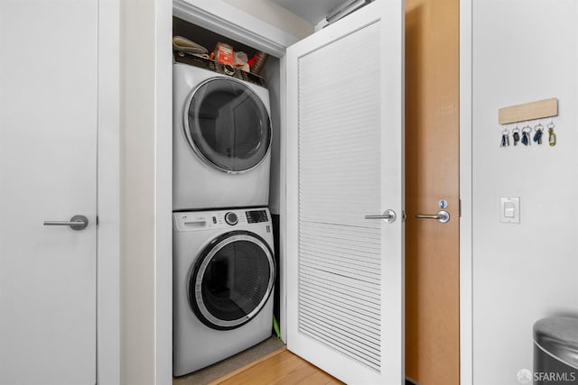 clothes washing area with hardwood / wood-style floors and stacked washer and dryer