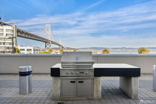 view of patio with a water and mountain view and a grill