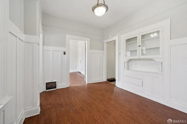 interior space featuring dark wood finished floors, visible vents, a decorative wall, and a wainscoted wall