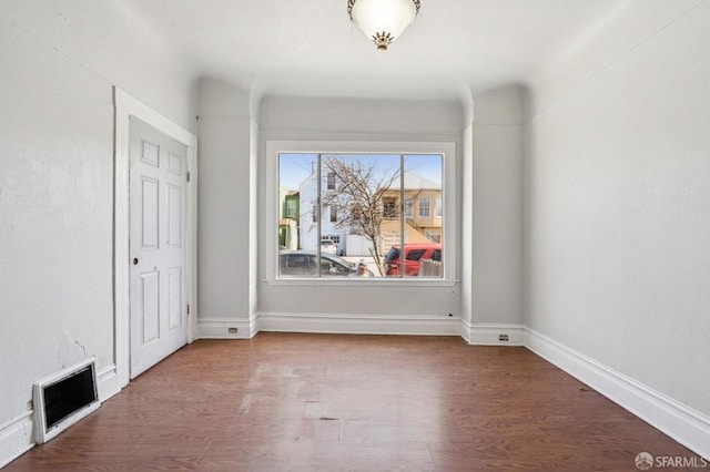 spare room featuring baseboards and wood finished floors