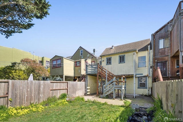 rear view of property featuring stairway and fence private yard