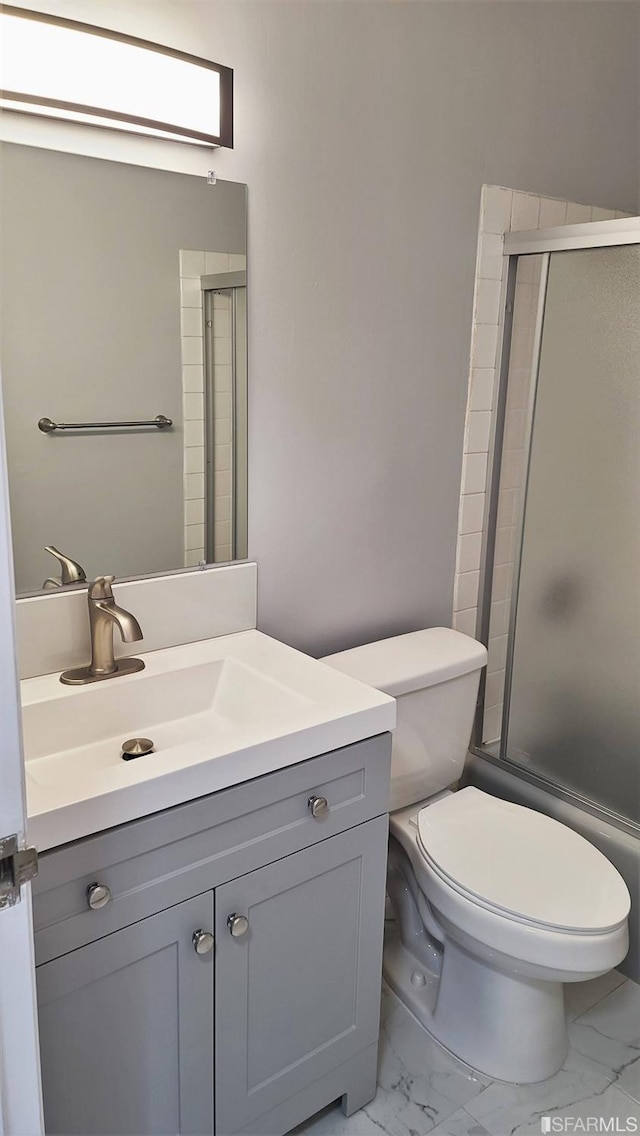 bathroom with vanity, a shower with shower door, and toilet