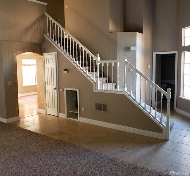 4400 Elk Dr, Antioch, CA 94531 - staircase with a high ceiling, arched walkways, baseboards, tile patterned flooring, and carpet flooring