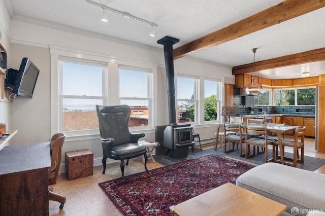 living room with baseboards, beam ceiling, a wood stove, ornamental molding, and baseboard heating